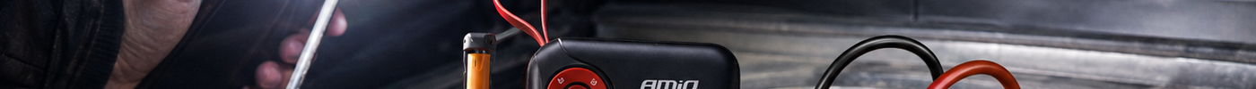 AMiO jumpstarter aangesloten op een lege autoaccu onder de motorkap in het donker